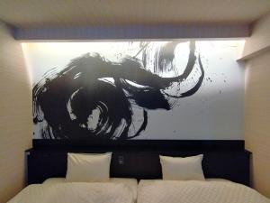 ein Bild eines Elefanten an einer Wand über einem Bett in der Unterkunft a-un（Luxury Hotel） in Kyoto