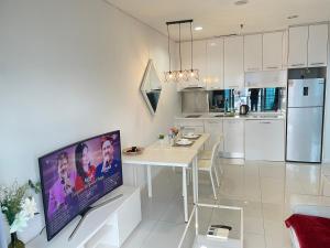 a white kitchen with a dining table and a tv at Summer suites klcc by Peaceful Nest in Kuala Lumpur