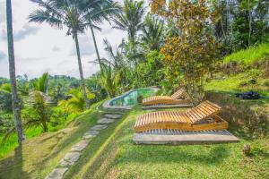 eine Reihe von Bänken in einem Park mit Pool in der Unterkunft Pesona Bali Ecolodge in Jatiluwih