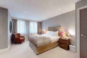 a bedroom with a large bed and a chair at Stunning, CastleView, Riverside, Modern Townhouse in Eton