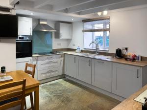 a kitchen with white cabinets and a sink and a table at Cyll Y Felin Fawr 1 in Aberdaron