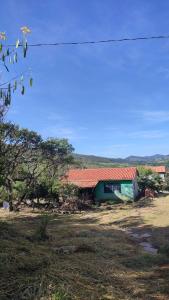 un bâtiment vert avec un toit rouge dans un champ dans l'établissement Casa da Vila Encantada, à São Thomé das Letras