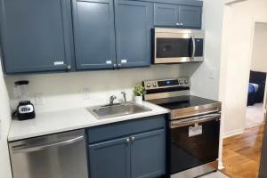 uma cozinha com armários azuis, um lavatório e um micro-ondas em Charming Home 5 Min From Downtown & At&t Center em San Antonio