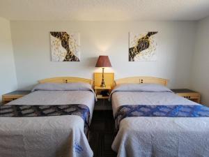 een kamer met 2 bedden en een tafel met een lamp bij Country garden hotel in Smoky Lake