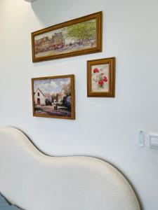 tres cuadros enmarcados en una pared blanca con una silla blanca en LAD Apartment & Homestay Hải Phòng - Hoàng Huy Grand Tower, en Hai Phong