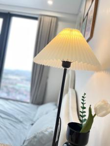 una lámpara con una planta en una olla junto a una cama en LAD Apartment & Homestay Hải Phòng - Hoàng Huy Grand Tower, en Hai Phong