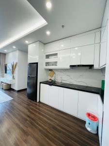cocina con armarios blancos y nevera negra en LAD Apartment & Homestay Hải Phòng - Hoàng Huy Grand Tower, en Hai Phong