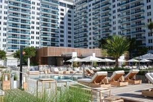 una piscina con tumbonas, sombrillas y edificios en Oceanview 1 Hotel & Homes 1 Bedroom 1 and Half Bathrooms Luxe Condo with Balcony, en Miami Beach