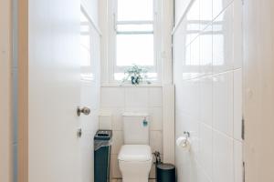 a white bathroom with a toilet and a window at Gaslight Inn - Adults Only in Sydney