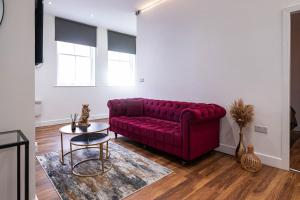 a living room with a red couch and a table at Manhattan Luxury Suites in Bradford