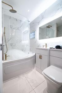 a white bathroom with a tub and a toilet at Manhattan Luxury Suites in Bradford