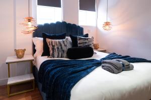 a bedroom with a blue and white bed with pillows at Manhattan Luxury Suites in Bradford
