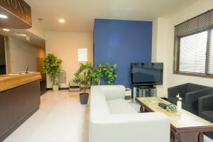 a living room with a white couch and a tv at Hotel Ina in Ina