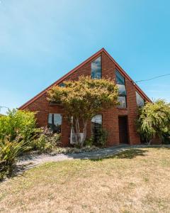 a brick house with a tree in front of it at Spacious Coastal Gem in Port Sorell