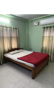 Suryalaxmi guest house في غاواهاتي: غرفة نوم مع سرير مع بطانية حمراء عليه