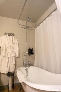 uma casa de banho com uma banheira e uma cortina de chuveiro branca em The Baker Hotel em Cranbrook