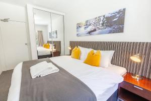 sypialnia z dużym białym łóżkiem z żółtymi poduszkami w obiekcie Lantern 1 Bedroom Balcony with Village and Mountain View w mieście Thredbo