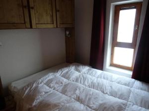 Una cama blanca en una habitación con ventana. en Résidence Fond Blanc - Studio pour 3 personnes à Arc 2000 proche des commerces et des pistes MAE-2149, en Arc 2000