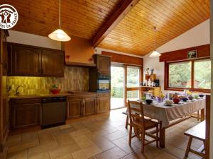a kitchen with wooden cabinets and a table with chairs at Villa d'architecte 200m² avec piscine privée et cheminée - FR-1-496-35 in Pommiers-en-Forez