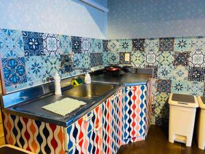 a kitchen with a sink and colorful tiles on the wall at 熱海星海台 星の輝きを導く石の小道 海景BBQの空間 大島を望む 日の出と夜景 in Atami