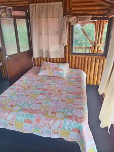 1 dormitorio con cama con edredón y ventana en Finca Turística Alto Bonito Filandia, en Filandia