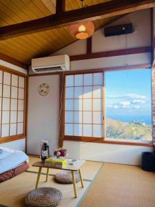 a room with a bed and a table and windows at 熱海星海台 星の輝きを導く石の小道 海景BBQの空間 大島を望む 日の出と夜景 in Atami