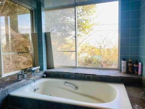 a bath tub in a bathroom with a window at 熱海星海台 星の輝きを導く石の小道 海景BBQの空間 大島を望む 日の出と夜景 in Atami