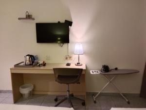um quarto com uma secretária, uma televisão e uma cadeira em hotel bintang em Kuala Lumpur
