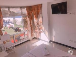 a living room with a large window and a tv at Hospedaje 3 Esquinas in Guatapé