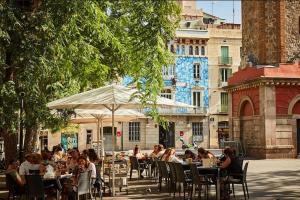 Studio Gracia By MyRentalHost في برشلونة: مجموعة من الناس يجلسون على الطاولات في مطعم خارجي