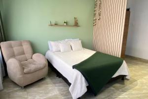 een slaapkamer met een bed en een stoel bij LOFT encantador, muy cómodo, al lado del MovistarA in Bogota