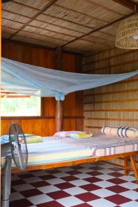 a bed in a wooden room with a mosquito net at Farmstay Sokfarm in Trà Vinh