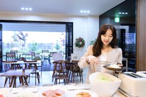 a woman is preparing food in a restaurant at Brown Dot Hotel Busan Station in Busan