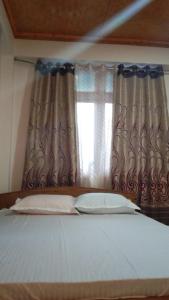 a bedroom with a bed and a window with curtains at Coral Homestay in Pelling