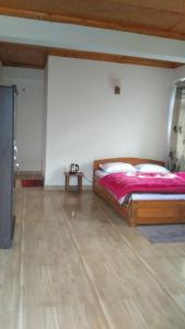 a bedroom with a bed and a wooden floor at Coral Homestay in Pelling