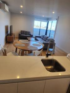 a kitchen and living room with a table and a sink at Modern Apartment Airport Area in Melbourne