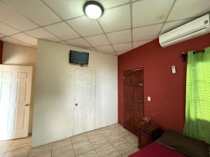 Villalobos Hotel Managua في ماناغوا: غرفة بها تلفزيون على الحائط وباب