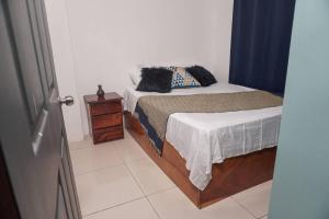 a small bedroom with a bed and a night stand at Nalu Home in San Francisco de Palmera