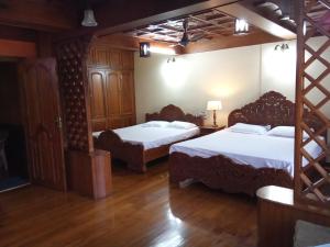 two beds in a room with wooden floors at Court View Homestay in Cochin