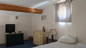 Un dormitorio con una cama y un televisor sobre una cómoda. en La voliere, en Toulon