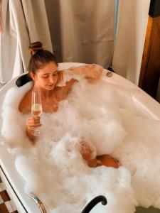 a woman sitting in a bath tub with a glass of wine at Cambará Ecomoradas in Cambará +48 photos