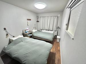 1 dormitorio con 2 camas, escritorio y ventana en 〈二人部屋〉駐車場無料&地下鉄駅から950m、札幌新築戸建、施設が豊富、最大三名可能 en Sapporo