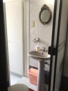 ein Bad mit einem Waschbecken und einem Wandspiegel in der Unterkunft Apartamento Dúplex - Barrio Maldonado Tunja in Tunja