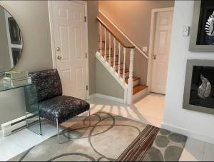 a living room with a chair and a staircase at Monthly Furnished Bright Beautiful 3bedroom Suite in Victoria