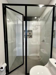 a bathroom with a toilet and a glass shower at INTO suites, suite de lujo in Armenia
