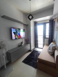 een woonkamer met een bank en een tv bij Staycation Near MOA by Cozypura with Pay Parking at S Res MOA in Manilla