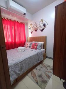 a bedroom with a bed with a red curtain at Staycation Near MOA by Cozypura with Pay Parking at S Res MOA in Manila