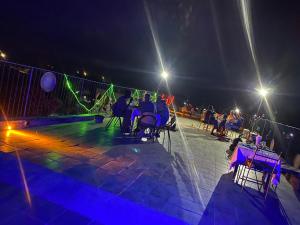 un grupo de personas sentadas en mesas en un patio por la noche en Hôtel évasion pêche djilor île sine saloum, en Fatick
