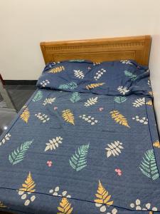 ein Bett mit einer blauen Bettdecke mit Blättern darauf in der Unterkunft Pin's House in Xã Tân Phát