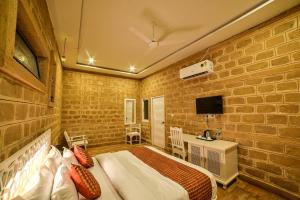 a bedroom with a bed and a desk and a tv at Desert Golden Palace in Jaisalmer